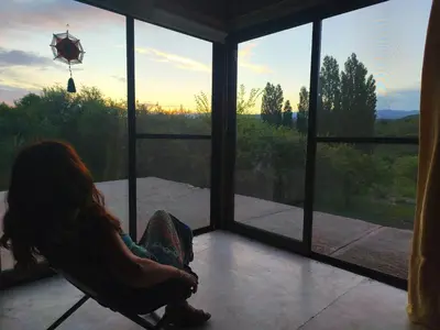 a woman sitting in a chair looking out of a window at Casas Serranas in La Bajada