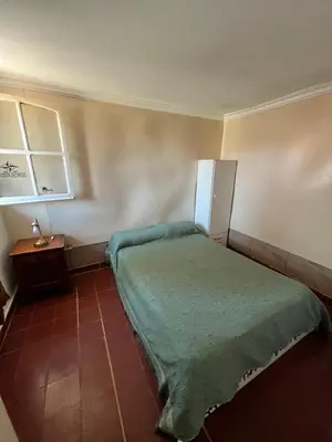 a small bedroom with a bed and a refrigerator at Cabaña AGU en Cabañas María in Villa Carlos Paz