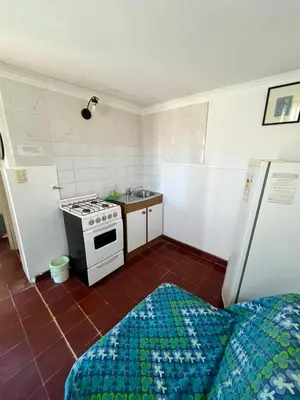 a small kitchen with a stove and a bed at Cabaña AGU en Cabañas María in Villa Carlos Paz