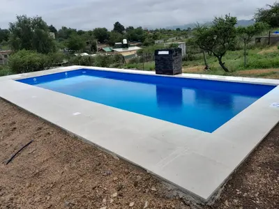 a swimming pool with blue water and a concrete floor at La casa de Daniel in Villa Santa Cruz del Lago