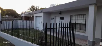 a fence in front of a white house at Almafuerte Alquiler Temporario in Almafuerte