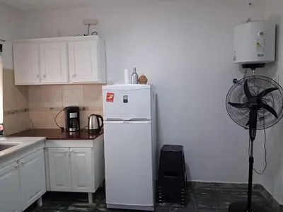 a kitchen with a white refrigerator and a fan at Almafuerte Alquiler Temporario in Almafuerte