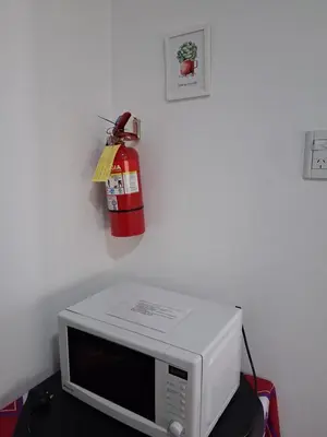 a fire extinguisher hanging on a wall above a microwave at Almafuerte Alquiler Temporario in Almafuerte