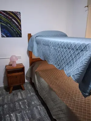 a bedroom with a bed with a blue comforter at Almafuerte Alquiler Temporario in Almafuerte