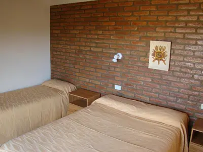 a room with two beds and a brick wall at Apartments Fazenda Solares in San Antonio de Arredondo