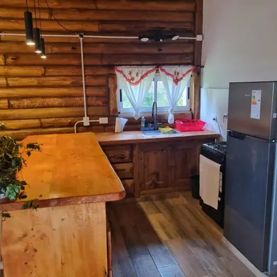a kitchen with wooden cabinets and a wooden counter top at Cabaña Cielos del Champaqui 6 kms VGB in Villa Ciudad Parque