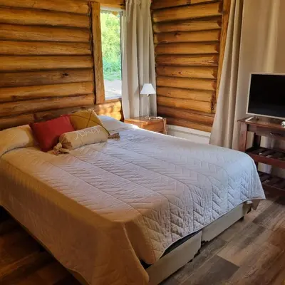 a bedroom with a large bed with a television at Cabaña Cielos del Champaqui 6 kms VGB in Villa Ciudad Parque