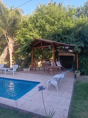 a patio with a table and chairs next to a pool at Cabaña frente al rio solo familias in Villa Carlos Paz