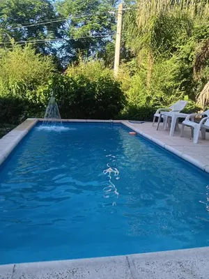 a swimming pool with a fountain in the water at Cabaña frente al rio solo familias in Villa Carlos Paz