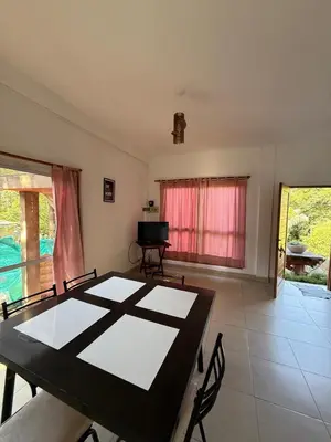 a dining room with a table and chairs and a television at Cabaña frente al rio solo familias in Villa Carlos Paz