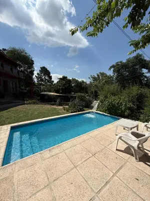 a swimming pool with two chairs and a table at Cabaña frente al rio solo familias in Villa Carlos Paz