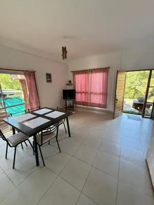 a dining room with a table and chairs and a piano at Cabaña frente al rio solo familias in Villa Carlos Paz