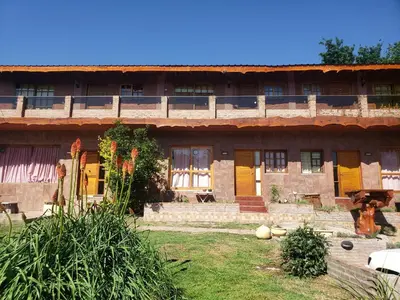 an old building with yellow doors and a yard at Cabaña frente al rio solo familias in Villa Carlos Paz