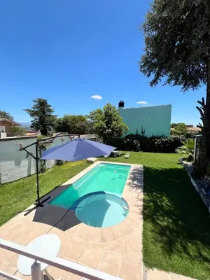 a swimming pool in a yard with an umbrella at Cabaña ELE en Cabañas María in Villa Carlos Paz