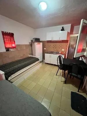 a room with a bed and a kitchen with a table at Cabaña EMI en Cabañas María in Villa Carlos Paz