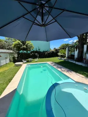 a swimming pool with an umbrella in a yard at Cabaña EMI en Cabañas María in Villa Carlos Paz