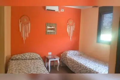 two beds in a room with orange walls at Iwoka Los Aromos in Villa Los Aromos