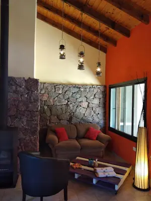 a living room with a couch and a stone wall at Complejo Aguas Calmas - Casa Laguna in Los Reartes