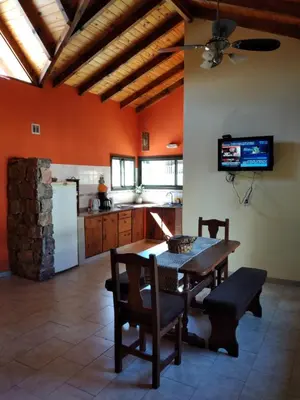 a kitchen with a table and chairs and a refrigerator at Complejo Aguas Calmas - Casa Laguna in Los Reartes