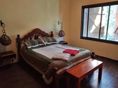 a bedroom with a large bed and a wooden table at Complejo Aguas Calmas - Casa Laguna in Los Reartes