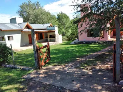 a house with a gate in front of a yard at Complejo Aguas Calmas - Casa Laguna in Los Reartes