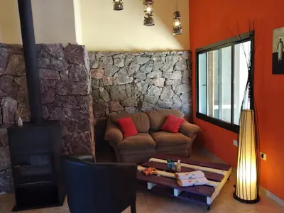 a living room with a couch and a stone wall at Complejo Aguas Calmas - Casa Laguna in Los Reartes