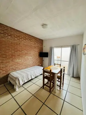 a bedroom with a bed and a table and a brick wall at Villanto apart Solo Adultos in Mina Clavero
