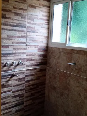 a bathroom with a glass shower with a brick wall at Sierras nuestras in Mina Clavero