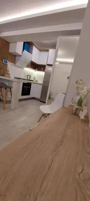 a kitchen with white cabinets and a wooden floor at departamento boutique centrico- villa carlos paz in Villa Carlos Paz