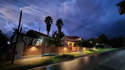 a house with a fence and palm trees at night at La Margarita Aparts - Solo 2 Pax in Mina Clavero