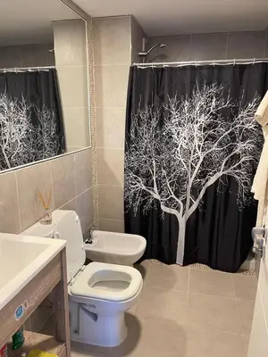 a bathroom with a toilet and a tree shower curtain at Depto 2 Dormitorios Pilay F Temporario in Cordoba