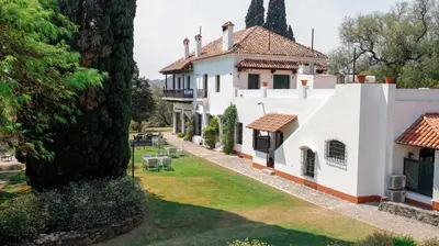 an exterior view of a white house with a yard at Hotel El Potrerillo de Larreta in Alta Gracia