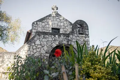 a stone building with a red flower in a garden at Hotel El Potrerillo de Larreta in Alta Gracia