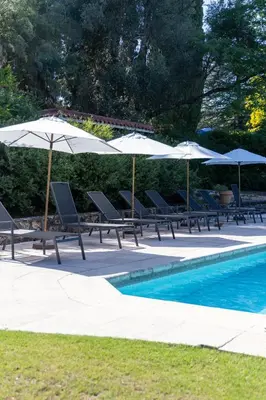a group of chairs and umbrellas next to a pool at Hotel El Potrerillo de Larreta in Alta Gracia