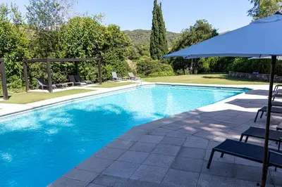 a swimming pool with chairs and an umbrella at Hotel El Potrerillo de Larreta in Alta Gracia