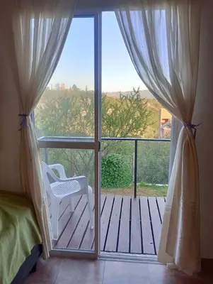 a bedroom with a balcony with a chair and a sliding glass door at vistas del valle in Villa Carlos Paz