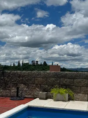 a brick wall with a swimming pool in front at vistas del valle in Villa Carlos Paz