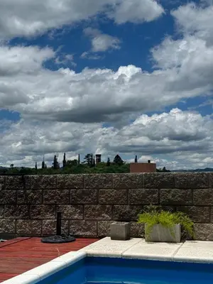 a brick wall with a swimming pool in front at vistas del valle in Villa Carlos Paz