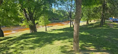 a group of trees in a park next to a river at Departamento Las Playas in Villa Carlos Paz