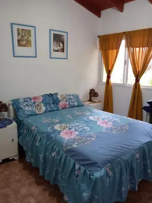 a bedroom with a bed with a blue comforter and two windows at Casa Milan in Villa General Belgrano