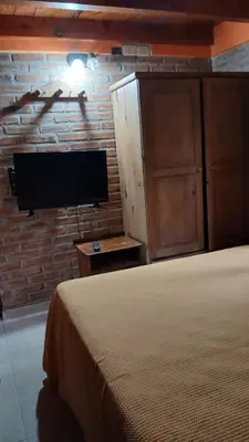 a bedroom with a bed and a tv on a brick wall at Cabañas Lago Azul in Villa Santa Cruz del Lago