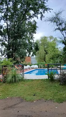 a swimming pool in a yard with a fence and trees at Cabañas Lago Azul in Villa Santa Cruz del Lago