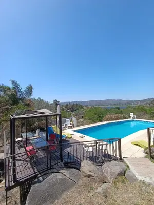 a patio with a table and chairs next to a swimming pool at Duplex con vista al Lago in Villa Carlos Paz