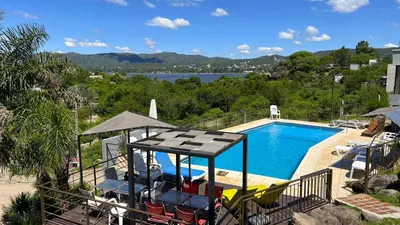 a view of a swimming pool with chairs and an umbrella at Duplex con vista al Lago in Villa Carlos Paz