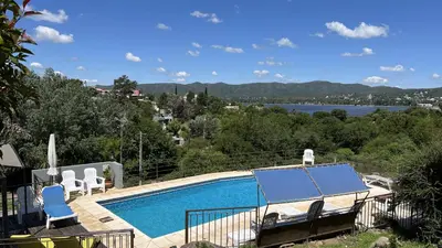 a swimming pool with chairs and a view of the water at Duplex con vista al Lago in Villa Carlos Paz