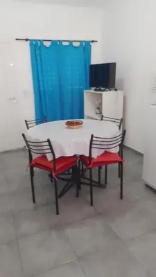 a table and chairs with a white table and a blue curtain at Departamento CR in Alta Gracia