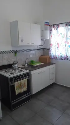 a kitchen with a stove and white cabinets at Departamento CR in Alta Gracia