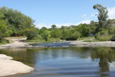 a river with rocks and trees in the background at Cabañas las marias 3 in Tanti Nuevo