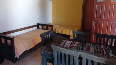 two beds in a room with a door and a bench at Cabañas las marias 3 in Tanti Nuevo