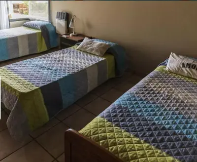 a room with two beds and a table with a window at Mirian house in Villa Carlos Paz
